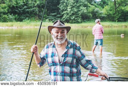 Men Fishing In River During Summer Day. Happy Fisherman Fishing In River Holding Fishing Rods. Trout