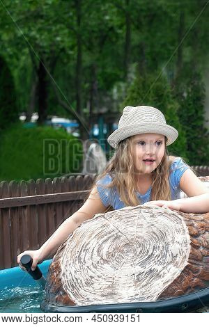 Cheerful Girl Preschooler In The Amusement Park Floats On A Boat On The Water And Enjoys This Little