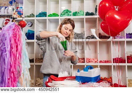 Woman Aerodesigner Fills Transparent Balloon With White Feathers Through Funnel