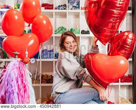 Woman On Red Decorative Barrel. With A Large Red Balloons In The Shape Of Heart.