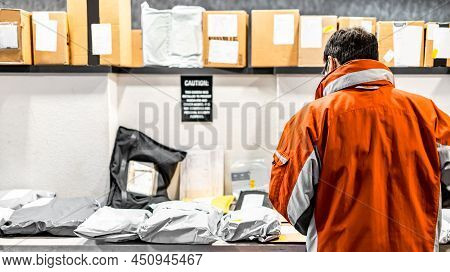 Man Standing At Mailroom Inside Apartment Looking For Packaging. Messenger Deliver Parcel Or Receive