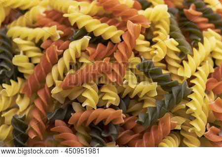 Three Colors Pasta Made From Durum Wheat. Pasta Fusilli Tricolor Background. Abstract Texture Of Col