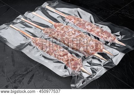 Raw Traditional Romanian Mititei In Vacuum Pack Set, On Black Dark Stone Table Background