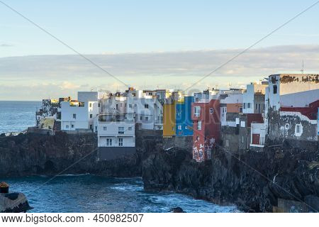 View On Colorful Houses And Black Lava Rocks In Small Village Punta Brava Near Puerto De La Cruz, Te
