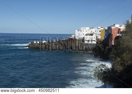 View On Colorful Houses And Black Lava Rocks In Small Village Punta Brava Near Puerto De La Cruz, Te