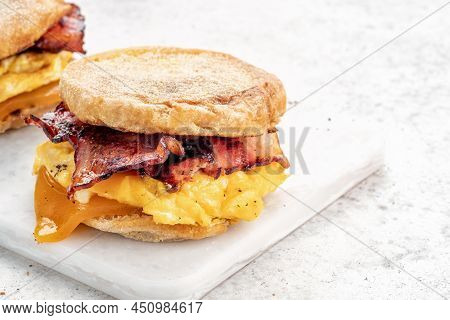 English Muffin, Scrumbled Egg, Ham, And Cheese Breakfast Sandwich On A Cutting Board