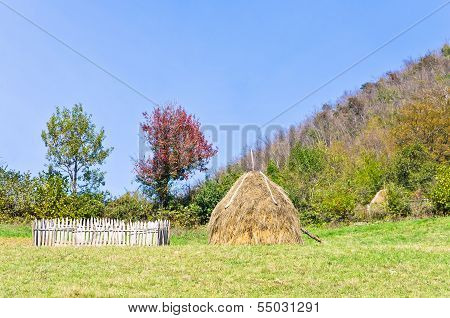 Hills on mount Bobija, small wooden fence, haystack and colorful trees
