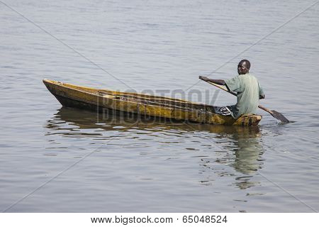 JUBA, SOUTH SUDAN-FEBRUARY 19 2013: unidentified man paddles traditionally made canoe on the White Nile through Juba, capital of South Sudan