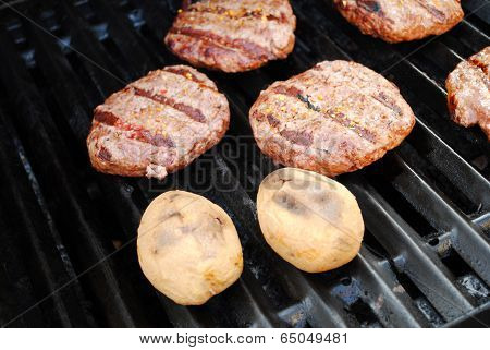 Two Whole Potatoes And Bugers On A Summer Grill