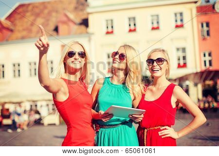 holidays and tourism concept - beautiful blonde girls toursits looking into tablet pc in the city