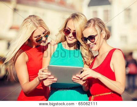 holidays and tourism concept - beautiful blonde girls toursits looking into tablet pc in the city