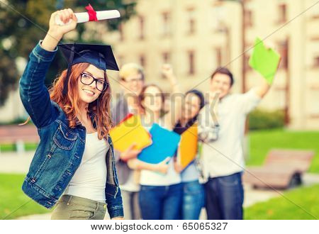 education, campus and teenage concept - smiling teenage girl in corner-cap and eyeglasses with diploma and classmates on the back