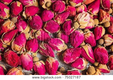 Dry tea rose buds on rustic wooden table