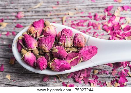 Dry rose buds on rustic wooden table
