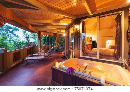 Beautiful Romantic Deck on Tropical Home with Bathtub, Candles, and Flowers at Sunset 