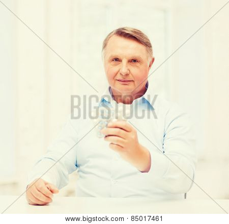 healthcare, madicine, pharmacy and elderly concept - old man with pack of pills