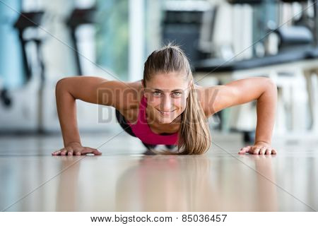 Gorgeous blonde woman warming up and doing some push ups a the gym