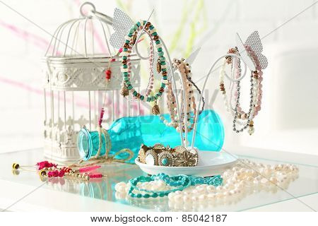 Decorative stand with jewelry and bijouterie on table in room