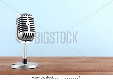 Retro microphone on wooden table on light background