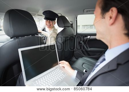 Businesswoman being chauffeured while working in the car