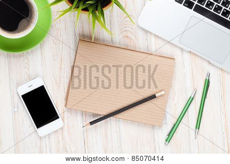 Office desk table with computer, supplies, coffee cup and flower. Top view with copy space