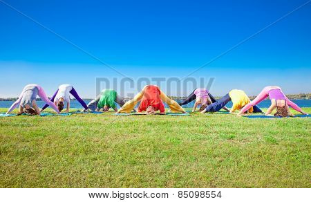 Young people practice Yoga asana on lakeside. Yoga concept.