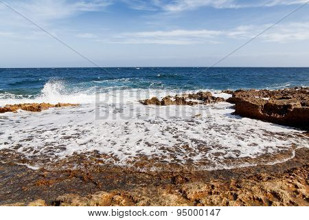 The Waves Beat Against The Rocky Shore. Water Flooded Depressions In The Rocks. Malta, Saint Julians