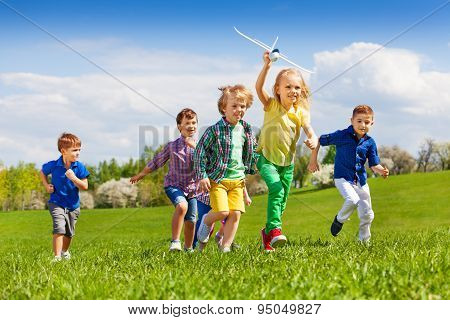 Group of happy running kids with white airplane