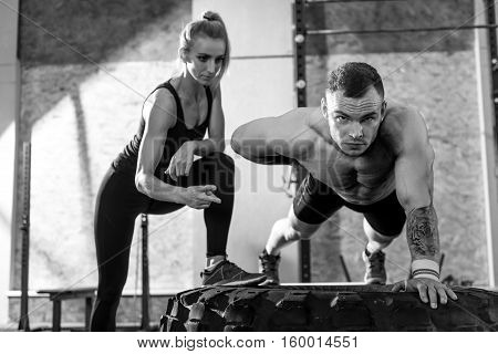 Workout partners. Nice pleasant good looking woman looking at the man and counting the amount of his push ups while working out in the gym