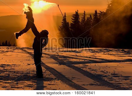 Father is playing with his children next to the snow cannon.