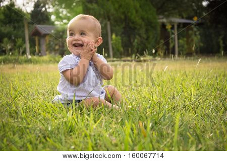 happy young baby child sittng on grass on beautiful summer day in park