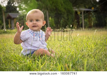 happy young baby child sittng on grass on beautiful summer day in park