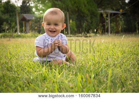 happy young baby child sittng on grass on beautiful summer day in park