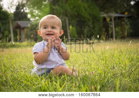 happy young baby child sittng on grass on beautiful summer day in park
