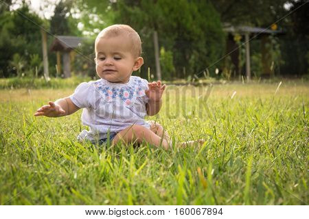 happy young baby child sittng on grass on beautiful summer day in park
