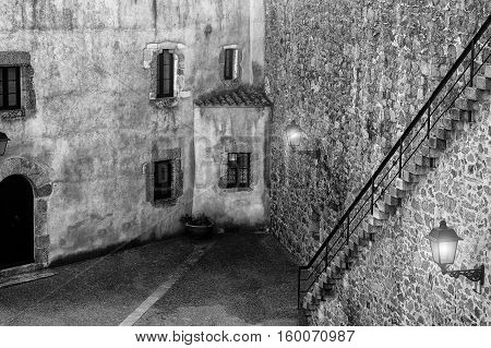 Beautiful view of scenic corner street with historic traditional houses in an old town in Europe with stone wall and ladder in summer sunny day with retro vintage black and white effect