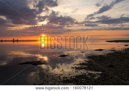 Pebble beach on the shore of Lake Baikal, the cloudy sunset sky