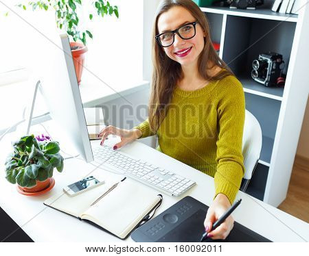 Young artist drawing something on graphic tablet at the home office