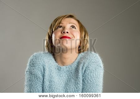 candid portrait of young beautiful and sweet woman in blue pullover smiling happy and cheerful in friendly face expression isolated on grey background in happiness concept