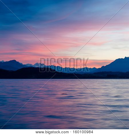 Romantic sunset over the lake in the Swiss Alps. Canton Zug. In the background the mountains silhouettes. High Dynamic Range Image