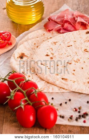 Piadina with ham and lettuce on wooden table.