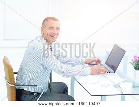 successful smiling businessman working on laptop at Desk in offi