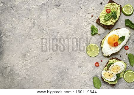 Assortment Of Avocado Toasts On A Concrete Or Slate Background.top View With Copy Space.