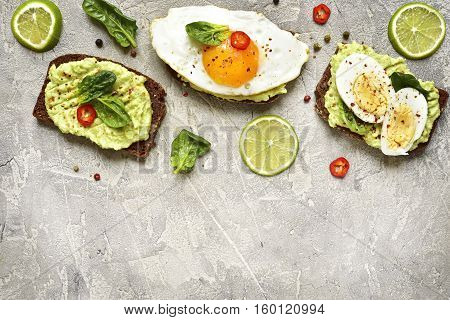 Assortment Of Avocado Toasts On A Concrete Or Slate Background.top View With Copy Space.