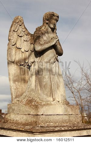 Figura de un ángel orando en un cielo azul