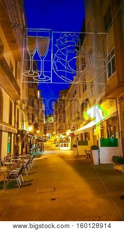La Coruna, Galicia, Spain - November 30, 2016: Night cityscape of La Coruna, Galicia, Spain. Illuminated street in the historic center of Coruna at blue evening hour