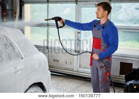 Man worker washing luxury car on a car wash.