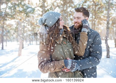 Smiling young couple looking at each other in winter park