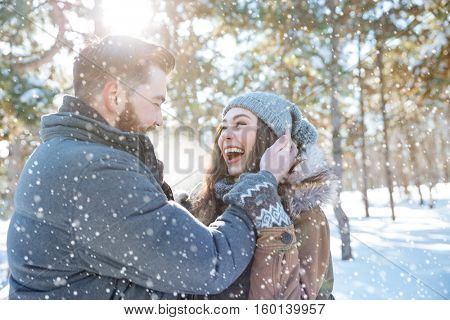 Cheerful young couple standing together in winter park