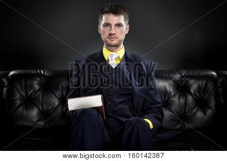Educated student or businessman with a book wearing a fashionable and stylish classic suit. He looks like a successfull academic bookworm or from an ivy league school